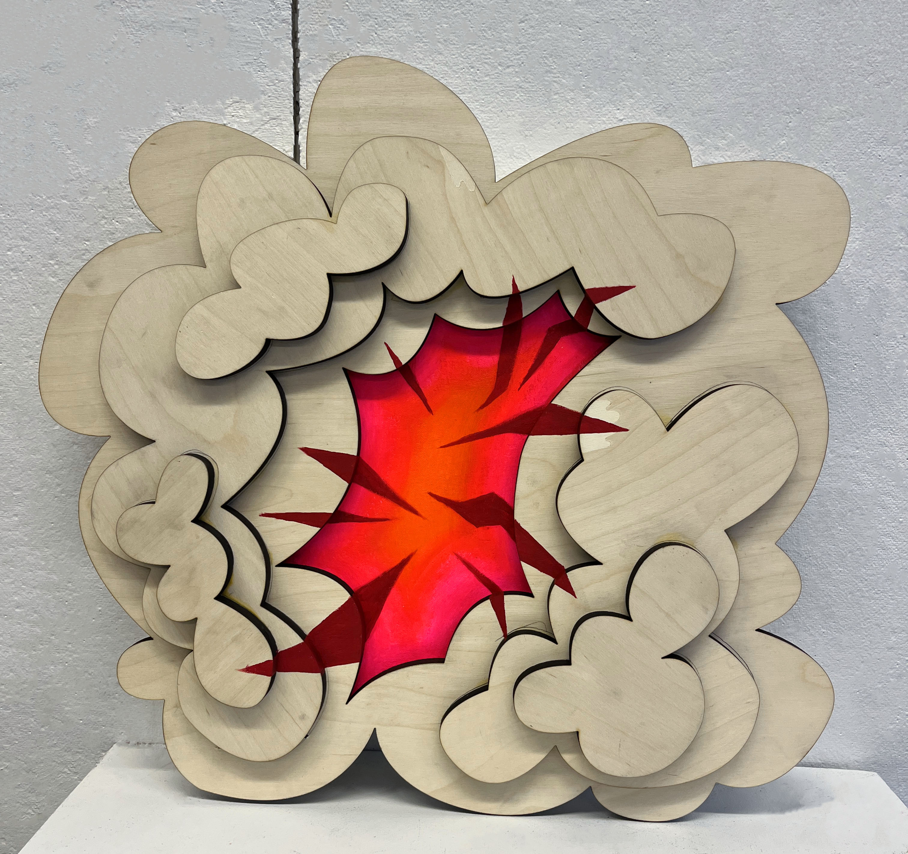 A layered wooden frame resembling the shape of a cloud frames a fluorescent pink and orange center with red spiked shooting out onto the wooden frame.